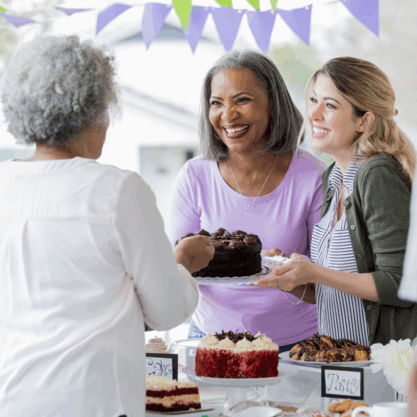 Women share a cake at a fundraising bake sale.