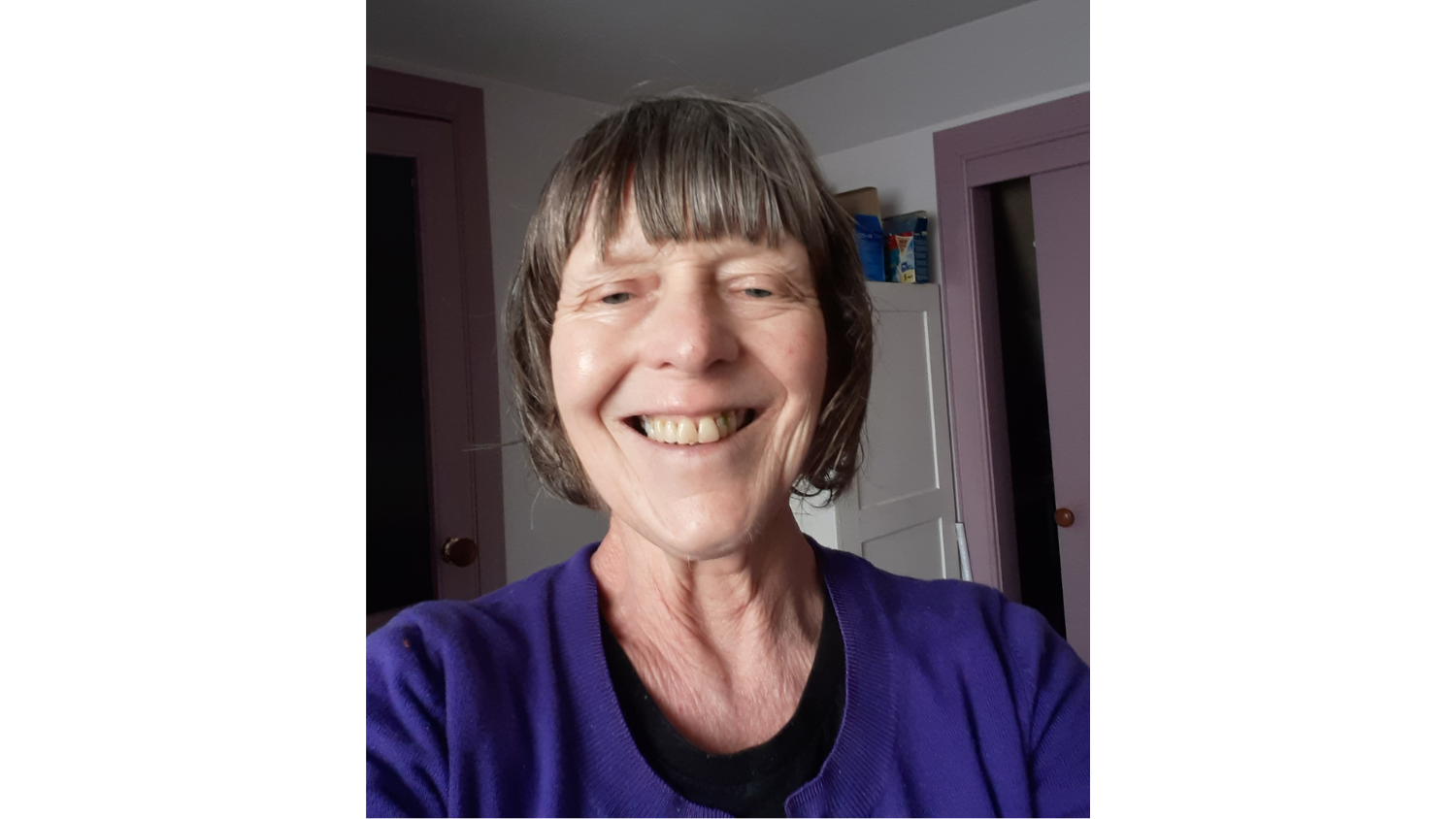 A woman in a navy blue blouse and bobbed brown hair smiles at the camera.
