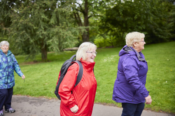 Three smiling women walking wearing waterproof jackets.