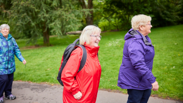 Three smiling women walking wearing waterproof jackets.