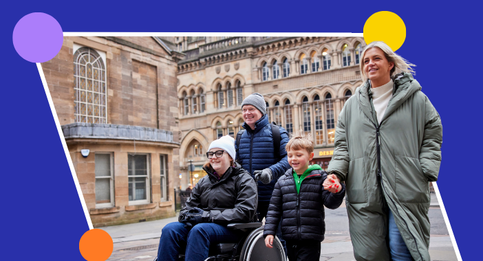 A small group of people smile as they walk and wheel along a city street.