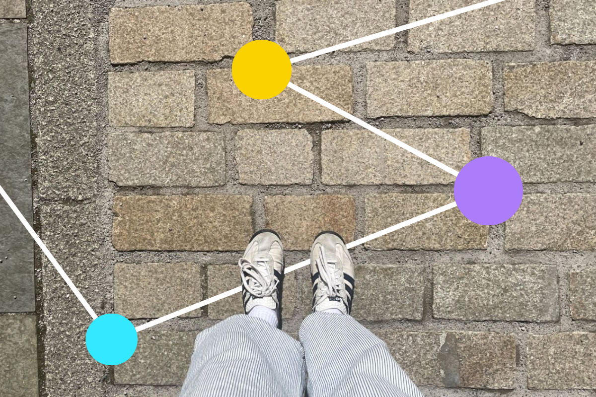 An downward shot of someone's white and black trainers on cobbled stones.